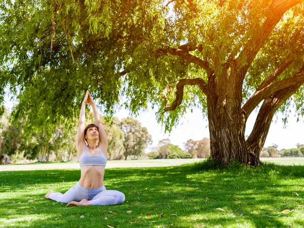 Jonge vrouw het beoefenen van yoga in het park — Stockfoto