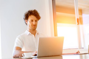 Adam evde dizüstü bilgisayarla çalışıyor.