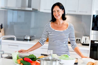 Mutfakta ayakta ve gülümseyen güzel kadın