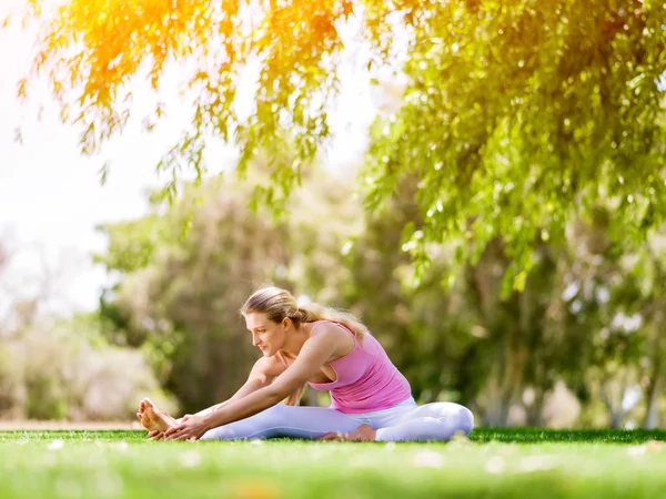 Parkta yoga yapan genç kadın. — Stok fotoğraf