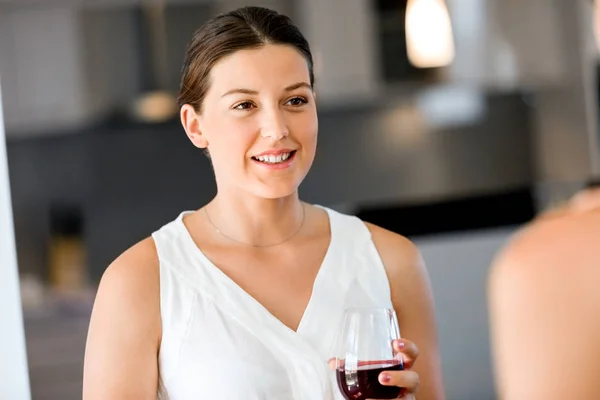 Mujer joven con su amigo sosteniendo una copa de vino en el interior — Foto de Stock