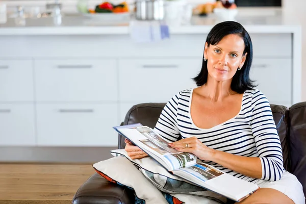 Gelukkige vrouw lezen van een boek zittend op een bank — Stockfoto