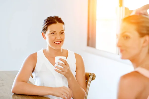 Giovane donna con la sua amica che prende il tè a casa — Foto Stock