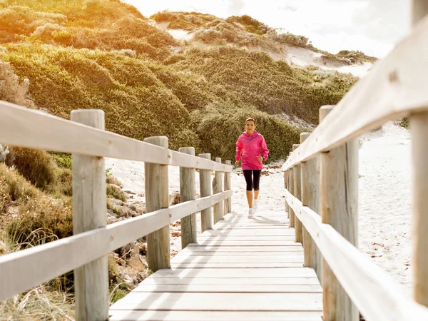 Jonge vrouw joggen op het strand — Stockfoto