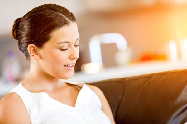 Glückliche Frau beim Lesen einer Zeitschrift auf einem Sofa sitzend — Stockfoto