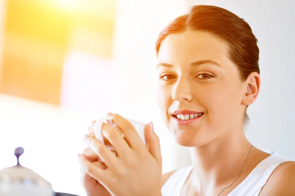 Giovane donna felice con una tazza di tè o caffè a casa — Foto Stock