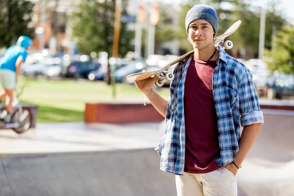 Adolescente con monopatín de pie al aire libre — Foto de Stock