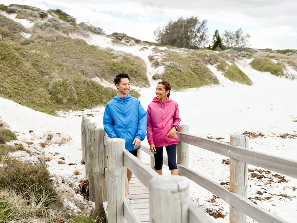 Joven hombre y mujer en ropa deportiva caminando por la playa — Foto de Stock