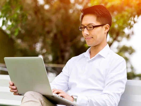 Молодой бизнесмен, сидя на улице, пользуется ноутбуком — стоковое фото