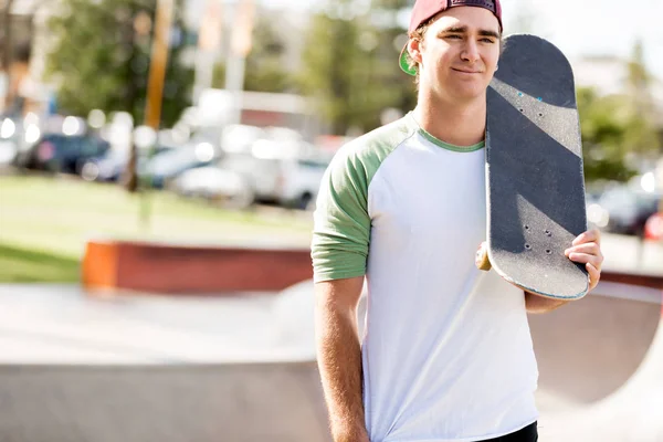 Adolescente con monopatín de pie al aire libre — Foto de Stock