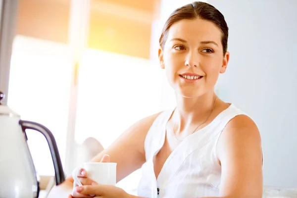 Счастливая молодая женщина с чашкой чая или кофе дома — стоковое фото