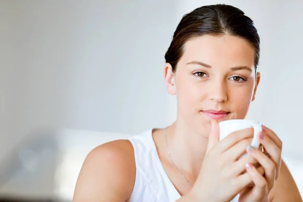 Glad ung kvinna med kopp te eller kaffe hemma — Stockfoto