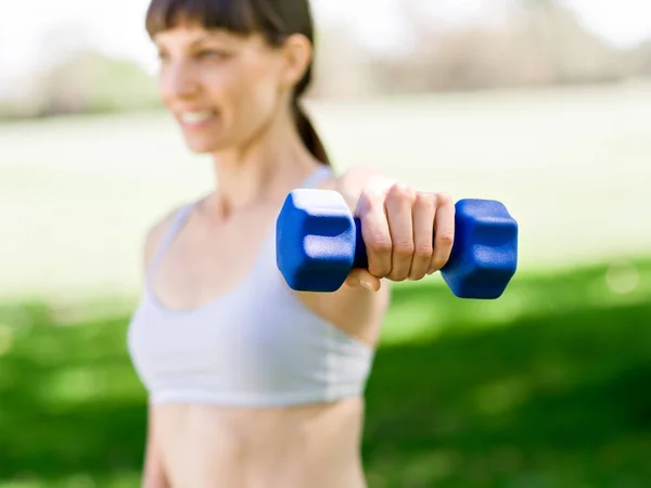 Porträt einer fröhlichen Frau in Fitnessbekleidung, die mit einer Hantel trainiert — Stockfoto