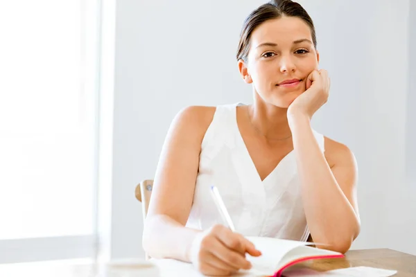 Young woman writing in an agenda at home or office — Stock Photo, Image