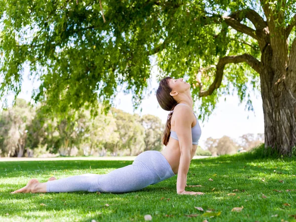 Jeune femme pratiquant le yoga dans le parc — Photo