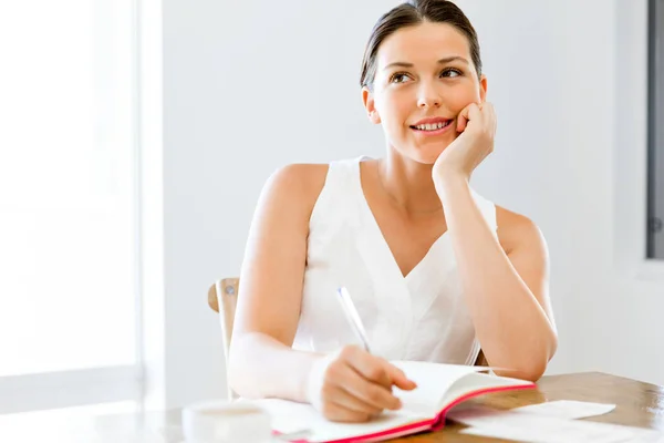 Jeune femme écrivant dans un agenda à la maison ou au bureau — Photo