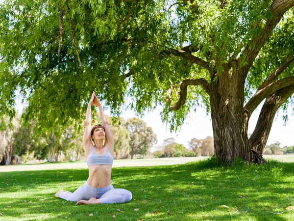 Genç kadın parkta yoga yapıyor. — Stok fotoğraf