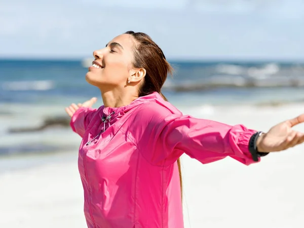 Sportieve vrouw in sportkleding staande aan de kust — Stockfoto