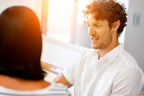 Portrait of man sitting and talking to woman indoors — Stock Photo, Image