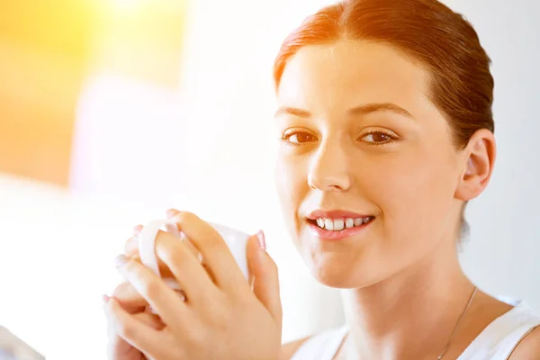 Happy young woman with cup of tea or coffee at home — Stock Photo, Image