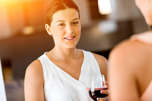 Młoda kobieta z jej przyjacielem, trzymając kieliszek wina w pomieszczeniu — Zdjęcie stockowe