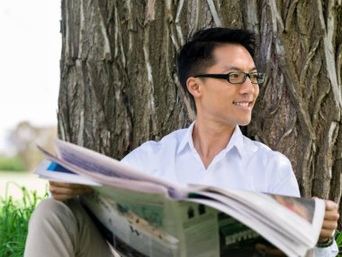 İş adamı parkta bir gazete okuyor