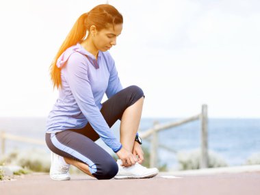 Kadın runner deniz kenarında bağcık bağlama