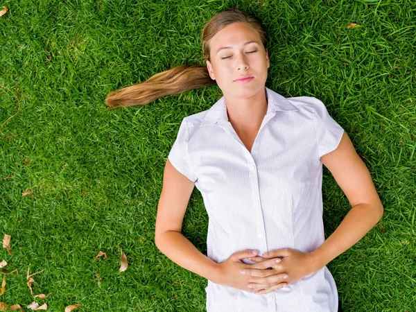 Mooie jonge vrouw ontspannen op een gras — Stockfoto