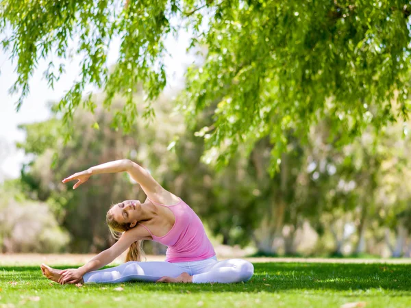 Jonge vrouw doet yoga in het park — Stockfoto