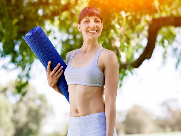 Junge Frau auf einer Turnmatte im Park — Stockfoto