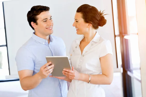 Νεαρός άνδρας και γυναίκα με touchpad στέκεται στο γραφείο — Φωτογραφία Αρχείου