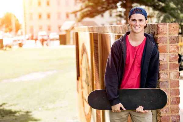 Dospívající chlapec s skateboard stojící venku — Stock fotografie