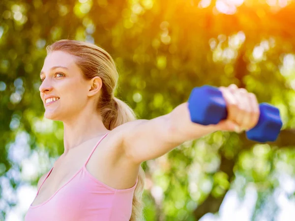 Porträt einer fröhlichen Frau in Fitnessbekleidung, die mit einer Hantel trainiert — Stockfoto