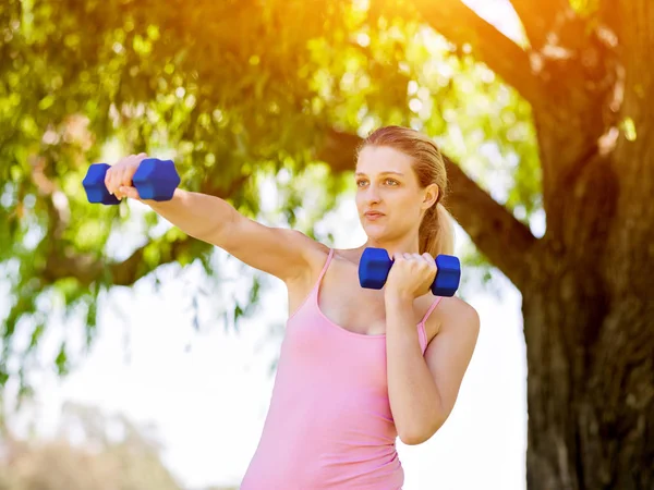 Retrato de mujer alegre en ropa de fitness haciendo ejercicio con mancuerna — Foto de Stock