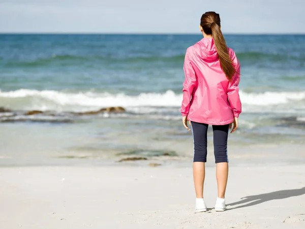 Mujer atlética en ropa deportiva de pie en la playa — Foto de Stock