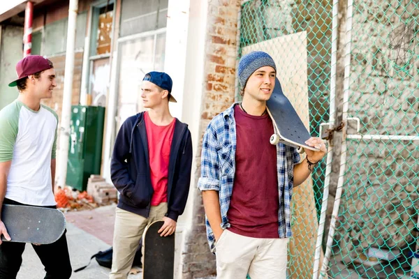 Amigos adolescentes caminando por la calle con patinetas — Foto de Stock