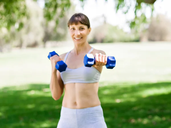 Retrato de mujer alegre en ropa de fitness haciendo ejercicio con mancuerna — Foto de Stock