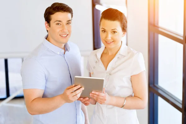 Jonge man en vrouw met touchpad staan in kantoor — Stockfoto