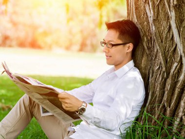 İş adamı parkta bir gazete okuyor