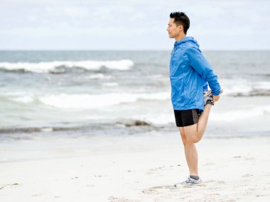 Genç adam sahilde egzersiz yaparak