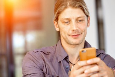 Kendine güvenen genç adam akıllı rahat kıyafet telefon tutarak