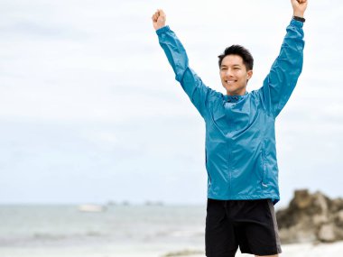 Sahilde uzanmış kolları olan genç adam