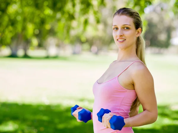Retrato de mujer alegre en ropa de fitness haciendo ejercicio con mancuerna —  Fotos de Stock