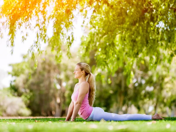 Parkta yoga yapan genç kadın. — Stok fotoğraf