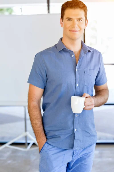 Young businessman in office with a mug — Stock Photo, Image