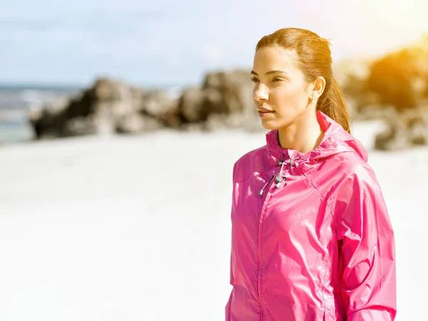 Atletisk kvinna i sportkläder stående vid havet — Stockfoto