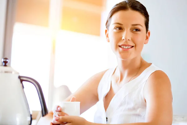 Jovem feliz com xícara de chá ou café em casa — Fotografia de Stock