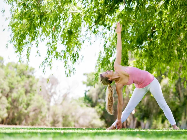 Mladá žena dělá jógu v parku — Stock fotografie