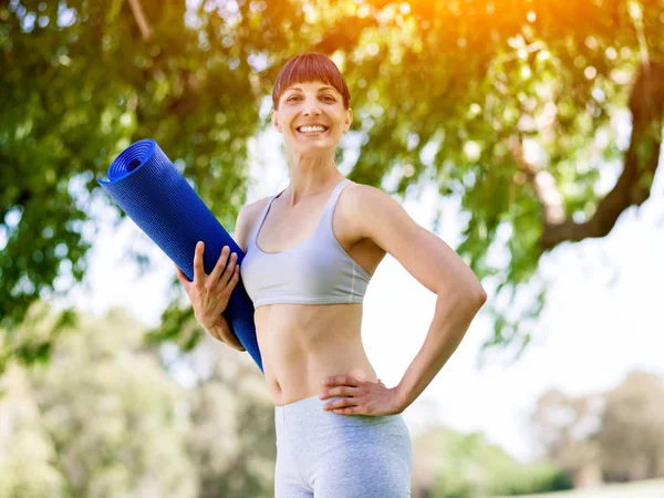 Junge Frau auf einer Turnmatte im Park — Stockfoto