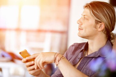 Kendine güvenen genç adam akıllı rahat kıyafet telefon tutarak